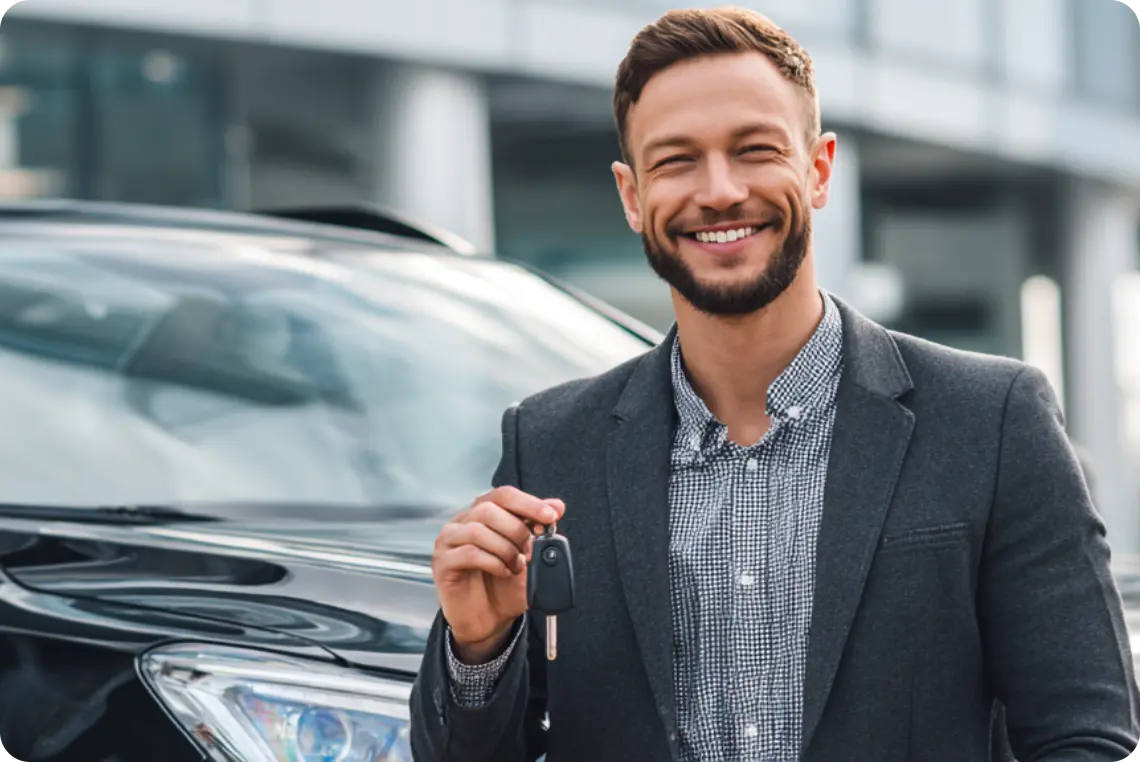 Man standing in front of a new car smiling holding keys